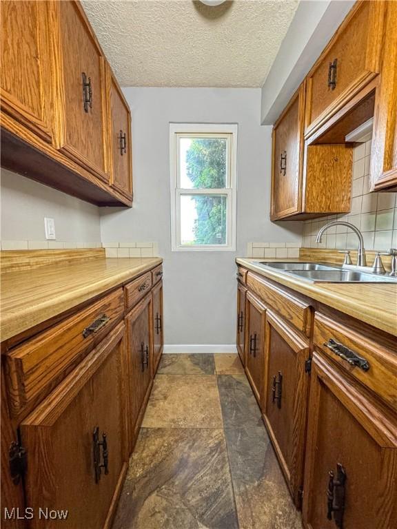 101 Ridgeway St, Struthers, OH 44471 - kitchen with brown cabinets, light countertops, backsplash, and a textured ceiling