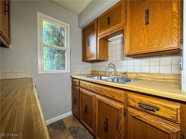 101 Ridgeway St, Struthers, OH 44471 - kitchen with backsplash, brown cabinets, light countertops, and dark stone finish flooring