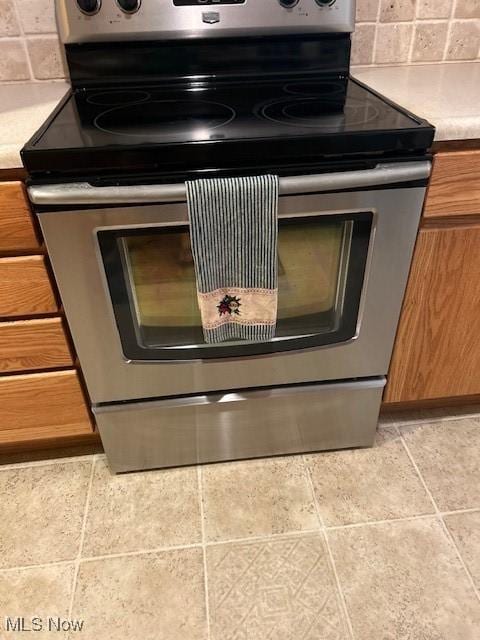 625 Canterbury Ln Unit 27A, Medina, OH 44256 - kitchen view of stainless steel electric range oven, brown cabinets, backsplash, and light countertops