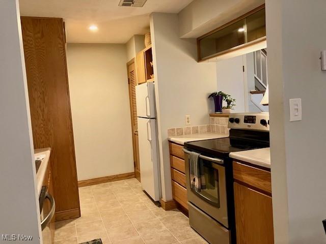 625 Canterbury Ln Unit 27A, Medina, OH 44256 - kitchen with stainless steel electric stove, freestanding refrigerator, brown cabinetry, light countertops, and oven