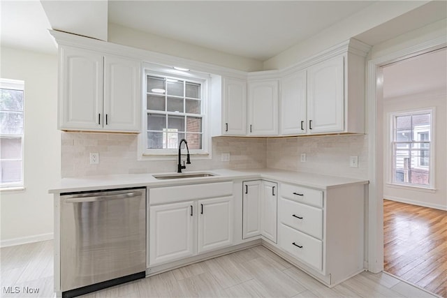 3886 Faversham Rd, University Heights, OH 44118 - kitchen featuring stainless steel dishwasher, white cabinetry, light countertops, and decorative backsplash