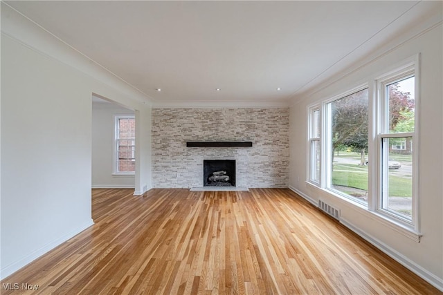 3886 Faversham Rd, University Heights, OH 44118 - unfurnished living room with light wood-style flooring, plenty of natural light, ornamental molding, and a stone fireplace