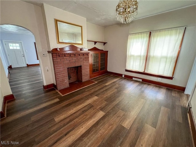 1874 Idaho Ave, East Liverpool, OH 43920 - unfurnished living room with arched walkways, a brick fireplace, wood finished floors, and a chandelier