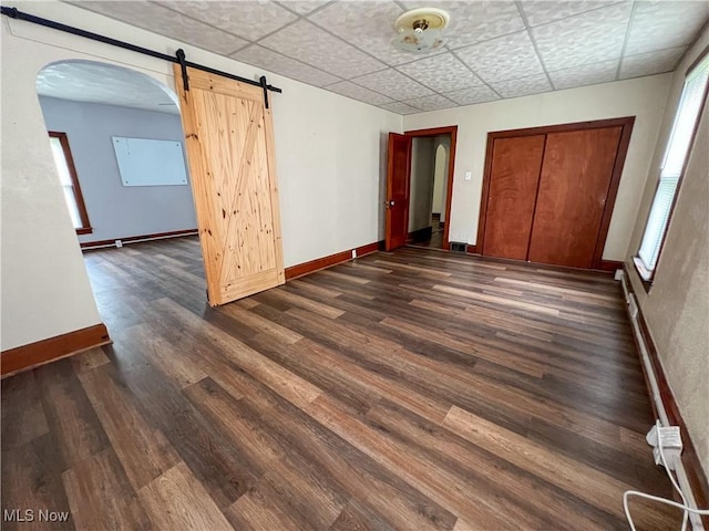 1874 Idaho Ave, East Liverpool, OH 43920 - empty room featuring healthy amount of natural light, dark wood-style flooring, a barn door, and arched walkways