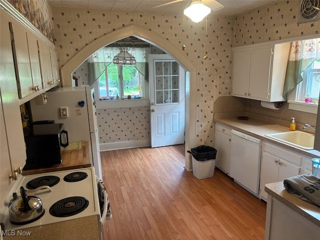 1051 Oakwood Ave NE, Massillon, OH 44646 - kitchen with wallpapered walls, white appliances, white cabinets, and light wood-style floors