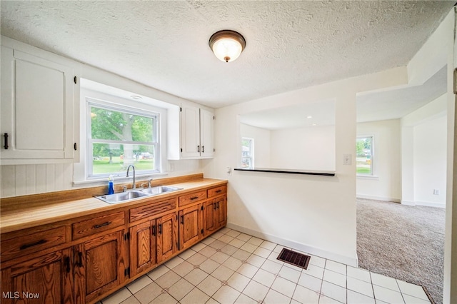 6136 Lake Rd W, Ashtabula, OH 44004 - kitchen with light colored carpet, a textured ceiling, brown cabinetry, white cabinets, and light tile patterned floors