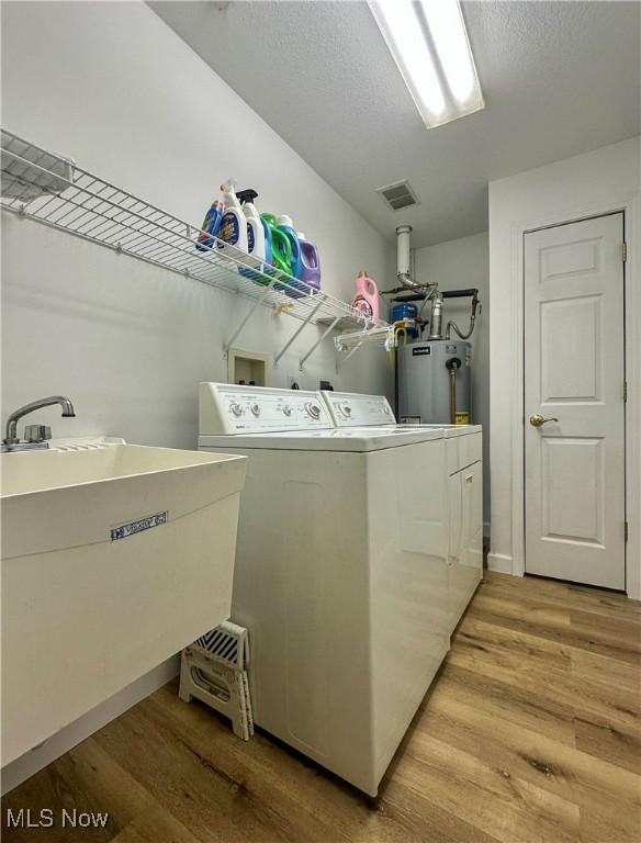203 Willow Brook Dr NE, Warren, OH 44483 - laundry room with separate washer and dryer, gas water heater, light wood-type flooring, and a textured ceiling