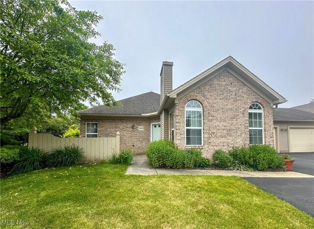 203 Willow Brook Dr NE, Warren, OH 44483 - view of front of home with brick siding, a chimney, a garage, asphalt driveway, and roof with shingles