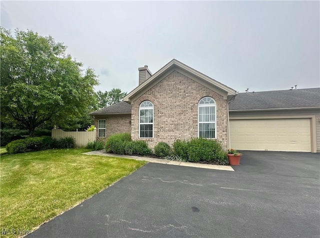 203 Willow Brook Dr NE, Warren, OH 44483 - view of home's exterior with driveway, a chimney, brick siding, and an attached garage