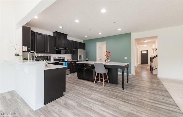3478 Shadow Ledge Dr, Twinsburg, OH 44087 - kitchen with stainless steel appliances, dark cabinetry, a kitchen bar, light countertops, and recessed lighting