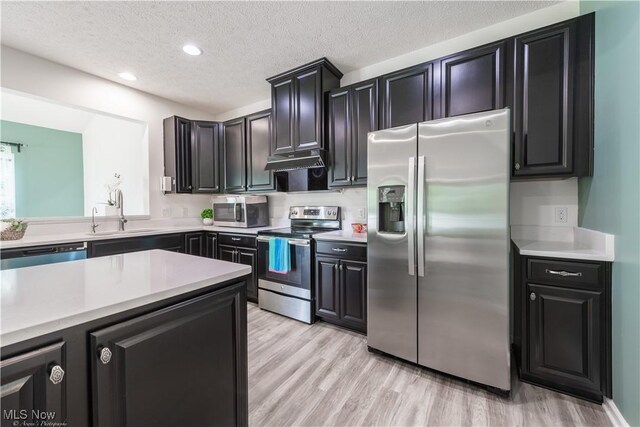 3478 Shadow Ledge Dr, Twinsburg, OH 44087 - kitchen with appliances with stainless steel finishes, under cabinet range hood, light countertops, light wood-type flooring, and a textured ceiling