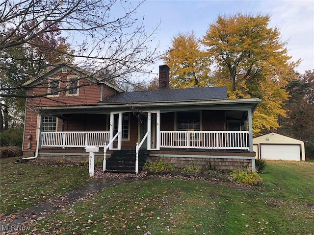 9117 N Main St, Windham, OH 44288 - view of front of property featuring covered porch, a chimney, a front yard, an outbuilding, and a detached garage
