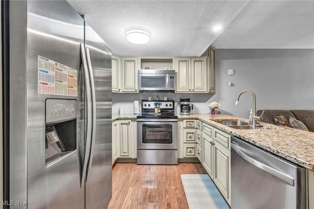 2709 Graham Rd, Stow, OH 44224 - kitchen with appliances with stainless steel finishes, cream cabinets, a textured ceiling, a peninsula, and light stone countertops