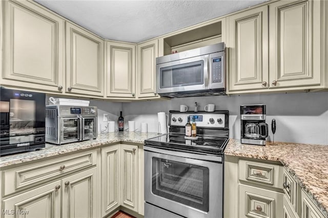 2709 Graham Rd, Stow, OH 44224 - kitchen with cream cabinets, stainless steel appliances, and light stone counters
