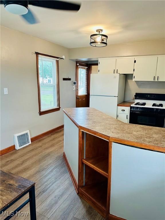 788 E Archwood Ave, Akron, OH 44306 - kitchen with freestanding refrigerator, gas range oven, light wood-type flooring, white cabinetry, and light countertops
