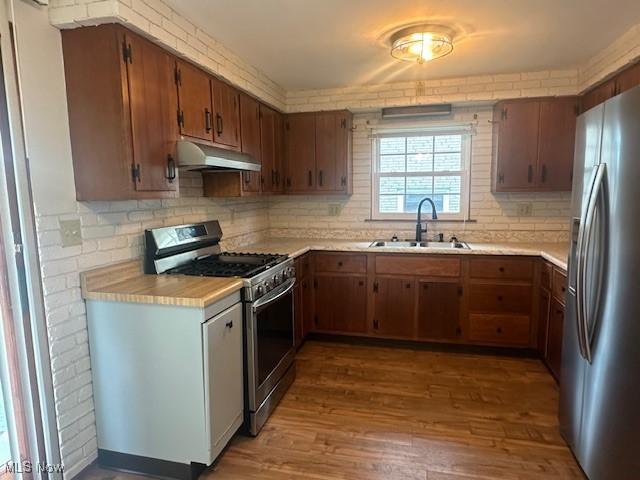 188 Court St, Follansbee, WV 26037 - kitchen featuring appliances with stainless steel finishes, under cabinet range hood, light countertops, tasteful backsplash, and wood finished floors