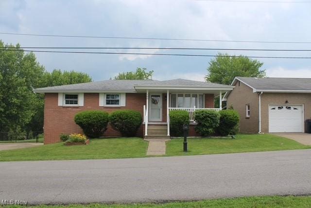 188 Court St, Follansbee, WV 26037 - view of front facade featuring a garage, concrete driveway, a front yard, brick siding, and a porch