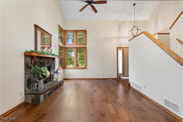 11095 Jan Cir NW, Uniontown, OH 44685 - unfurnished living room featuring high vaulted ceiling, a ceiling fan, wood-type flooring, a fireplace, and a chandelier