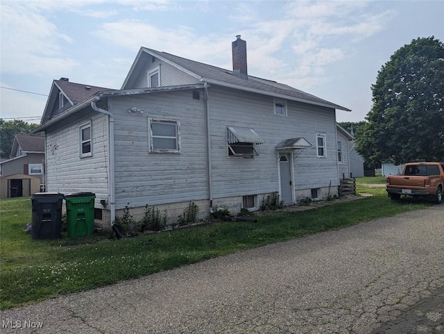 143 2nd St SE, Strasburg, OH 44680 - view of side of home featuring a chimney and a lawn