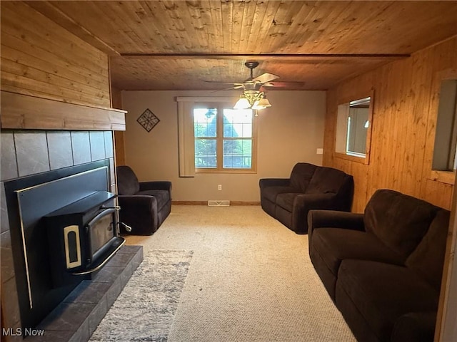 2484 Township Road 262, Bergholz, OH 43908 - living room with wood ceiling, wooden walls, a wood stove, ceiling fan, and dark carpet
