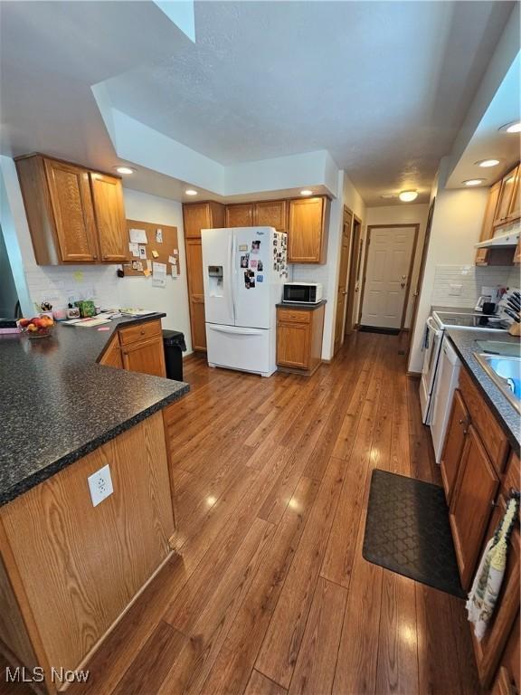 3925 N Wedgewood Dr, Mcconnelsville, OH 43756 - kitchen with white fridge with ice dispenser, stainless steel range with electric cooktop, wood-type flooring, decorative backsplash, and dark countertops