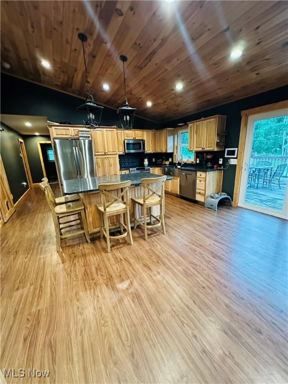 62063 Savage Rd, Cambridge, OH 43725 - kitchen with stainless steel appliances, lofted ceiling, dark countertops, a kitchen island, and light wood-type flooring