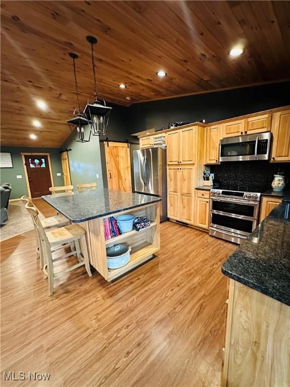 62063 Savage Rd, Cambridge, OH 43725 - kitchen featuring appliances with stainless steel finishes, light wood-type flooring, dark stone countertops, a kitchen island, and backsplash