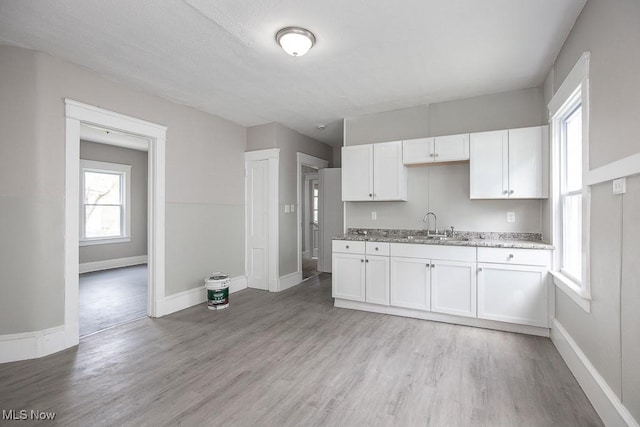 15517 Kipling Ave, Cleveland, OH 44110 - kitchen featuring white cabinets, light wood-style floors, and healthy amount of natural light