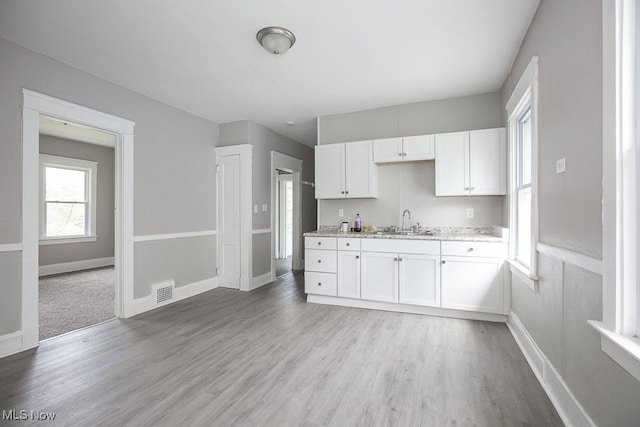 15517 Kipling Ave, Cleveland, OH 44110 - kitchen featuring white cabinetry, light wood-type flooring, and light stone counters