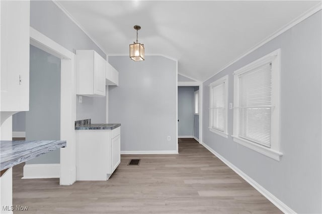 3009 Delmar Ave, Cleveland, OH 44109 - kitchen with white cabinets, ornamental molding, vaulted ceiling, light wood-style floors, and decorative light fixtures