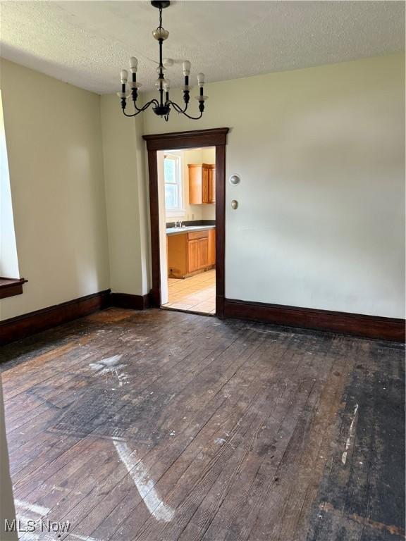 1225 Shorb Ave NW, Canton, OH 44703 - unfurnished room with light wood-style floors, a chandelier, and a textured ceiling