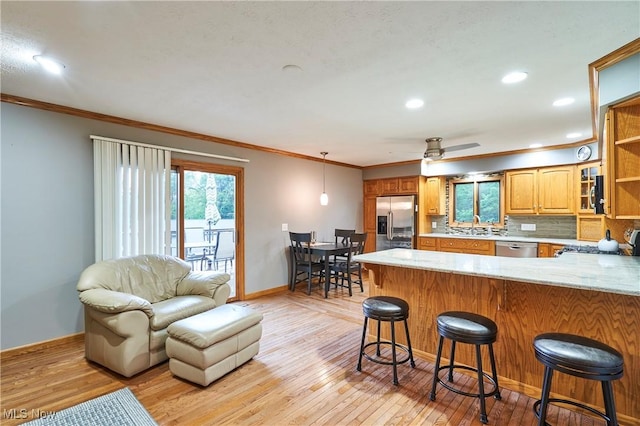 3145 Franks Rd, Clinton, OH 44216 - kitchen featuring appliances with stainless steel finishes, crown molding, a peninsula, light wood-style flooring, and a kitchen breakfast bar