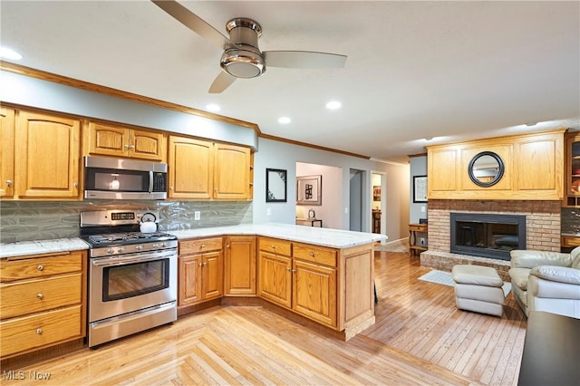 3145 Franks Rd, Clinton, OH 44216 - kitchen with appliances with stainless steel finishes, crown molding, a peninsula, a ceiling fan, and open floor plan