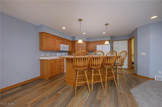 1011 Sequoia Dr NW, Strasburg, OH 44680 - kitchen with white appliances, wood finished floors, light countertops, recessed lighting, and pendant lighting