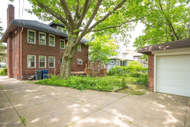2611 Exeter Rd, Cleveland Heights, OH 44118 - view of front of home with brick siding, a chimney, a wooden deck, concrete driveway, and a garage