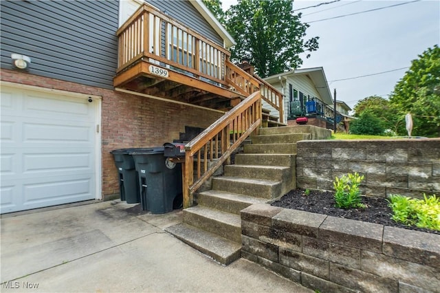 1399 Neptune Ave, Akron, OH 44301 - property entrance featuring a garage, concrete driveway, a deck, and brick siding
