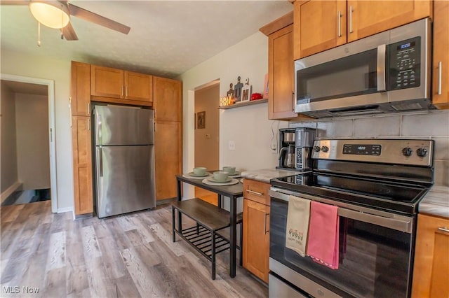 1399 Neptune Ave, Akron, OH 44301 - kitchen featuring stainless steel appliances, light countertops, light wood finished floors, ceiling fan, and brown cabinets