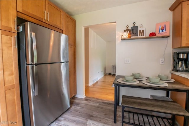 1399 Neptune Ave, Akron, OH 44301 - kitchen featuring freestanding refrigerator, light wood finished floors, and brown cabinets