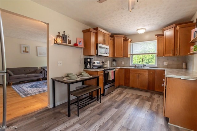 1399 Neptune Ave, Akron, OH 44301 - kitchen with appliances with stainless steel finishes, wood finished floors, light countertops, tasteful backsplash, and a textured ceiling