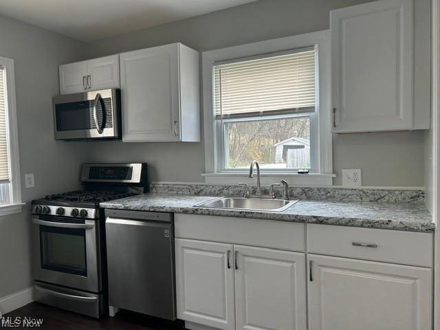 1975 9th St SW, Akron, OH 44314 - kitchen featuring stainless steel appliances, white cabinetry, dark wood-type flooring, and light stone countertops