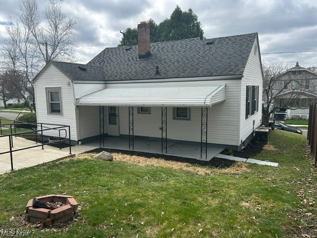 1975 9th St SW, Akron, OH 44314 - rear view of property featuring a yard, a chimney, a patio area, roof with shingles, and a fire pit