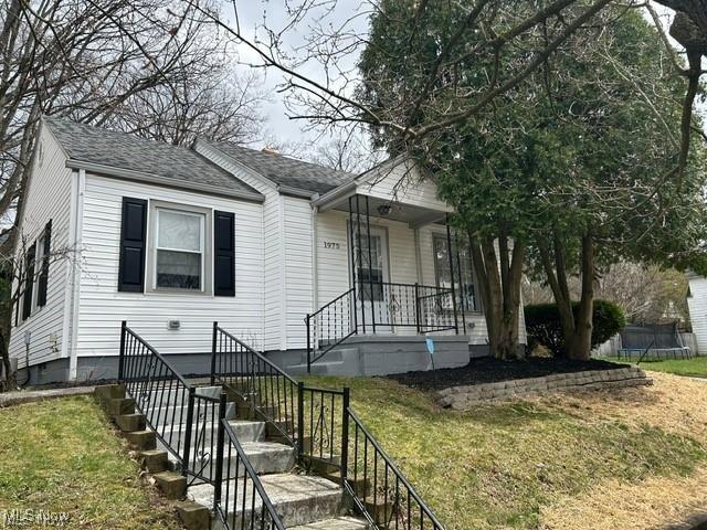 1975 9th St SW, Akron, OH 44314 - view of front of home with a trampoline, a porch, a front yard, and stairway