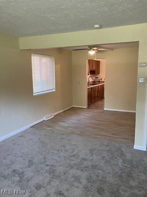4958 Caroline Dr Unit 6, Warrensville Heights, OH 44128 - unfurnished living room featuring dark carpet, ceiling fan, a textured ceiling, and dark wood-style flooring