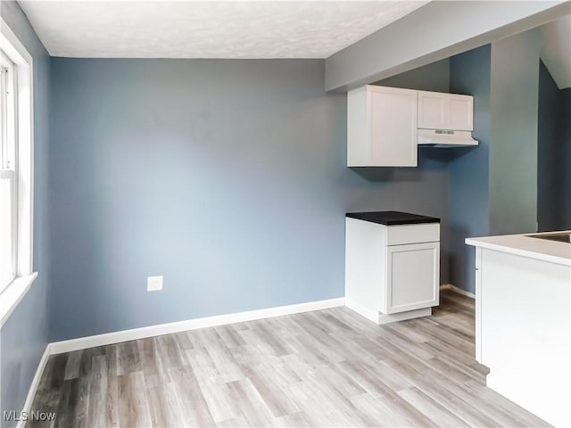1229 W 45th St, Ashtabula, OH 44004 - kitchen with under cabinet range hood, white cabinetry, and light wood finished floors