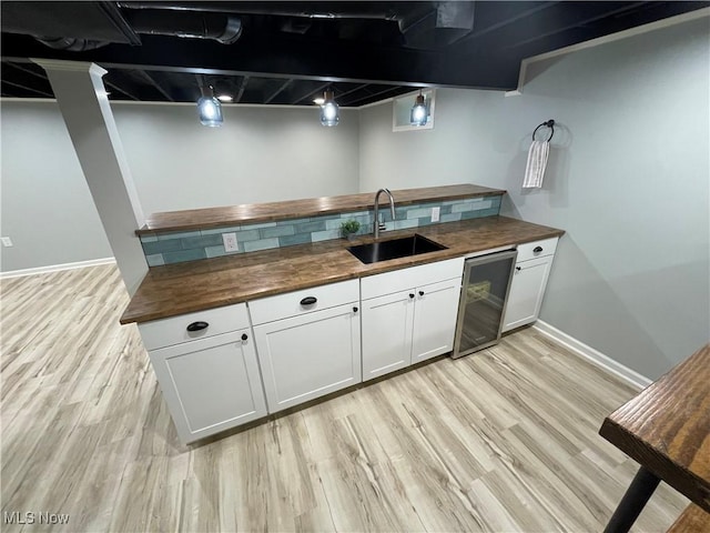 16005 Walvern Blvd, Maple Heights, OH 44137 - kitchen featuring butcher block countertops, light wood-style floors, white cabinetry, and beverage cooler