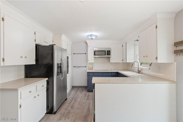 541 Broad St, Wadsworth, OH 44281 - kitchen featuring appliances with stainless steel finishes, tasteful backsplash, white cabinets, light countertops, and light wood-type flooring