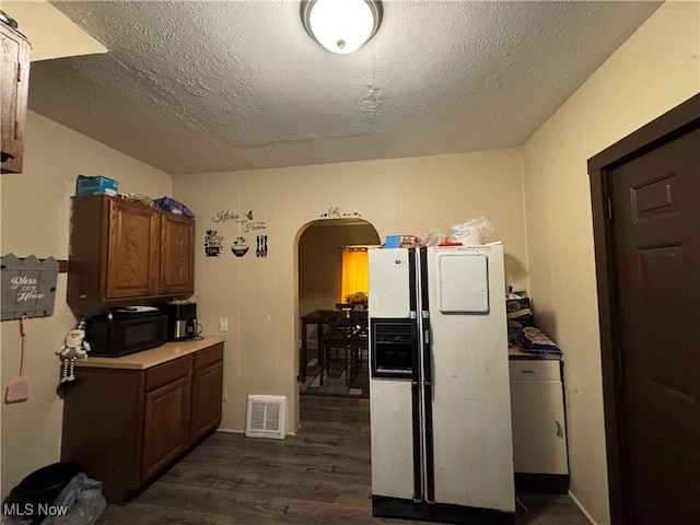 1201 Jackson St SW, Massillon, OH 44647 - kitchen with white refrigerator with ice dispenser, arched walkways, dark wood finished floors, a textured ceiling, and black microwave