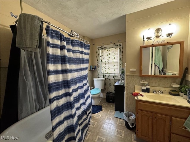 1201 Jackson St SW, Massillon, OH 44647 - full bathroom with vanity, a shower with curtain, a textured ceiling, tile walls, and wainscoting