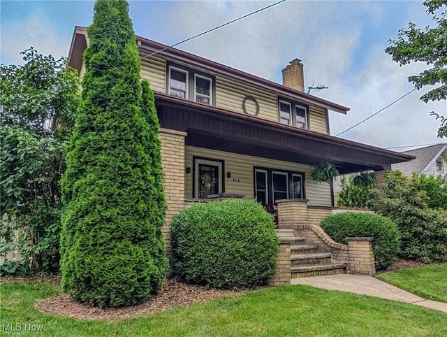 414 W Maple St, Hartville, OH 44632 - view of front of house with a porch, brick siding, a chimney, and a front yard