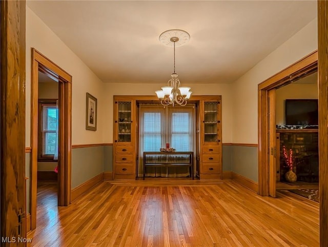 414 W Maple St, Hartville, OH 44632 - unfurnished dining area with light wood-type flooring, a chandelier, and plenty of natural light